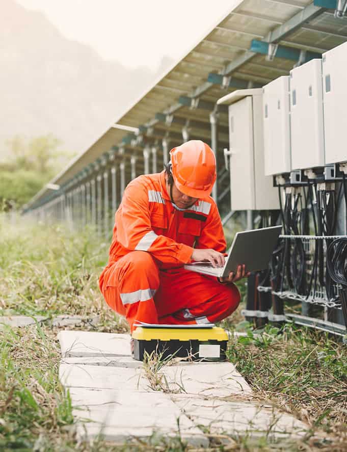 Engineer kneeling by transformers at a solar farm